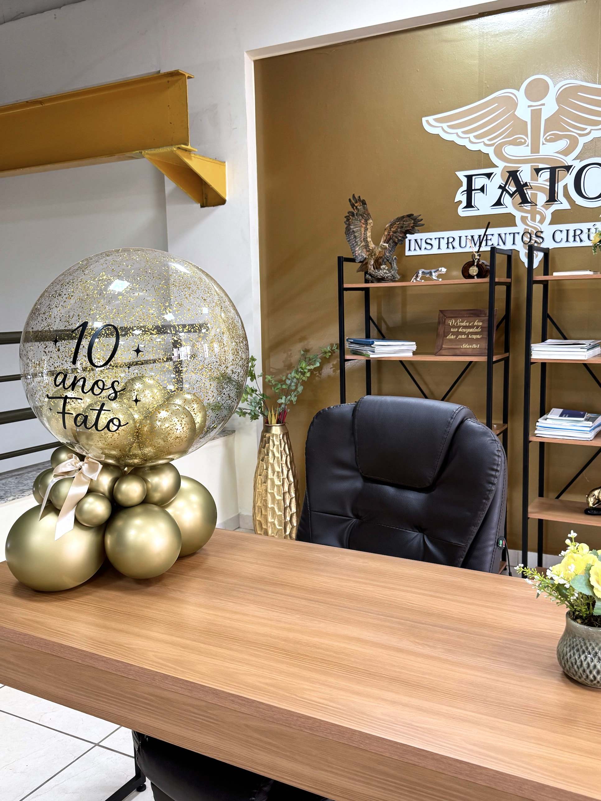 Recepção da FATO com balão comemorativo de 10 anos e a logo na parede ao fundo.