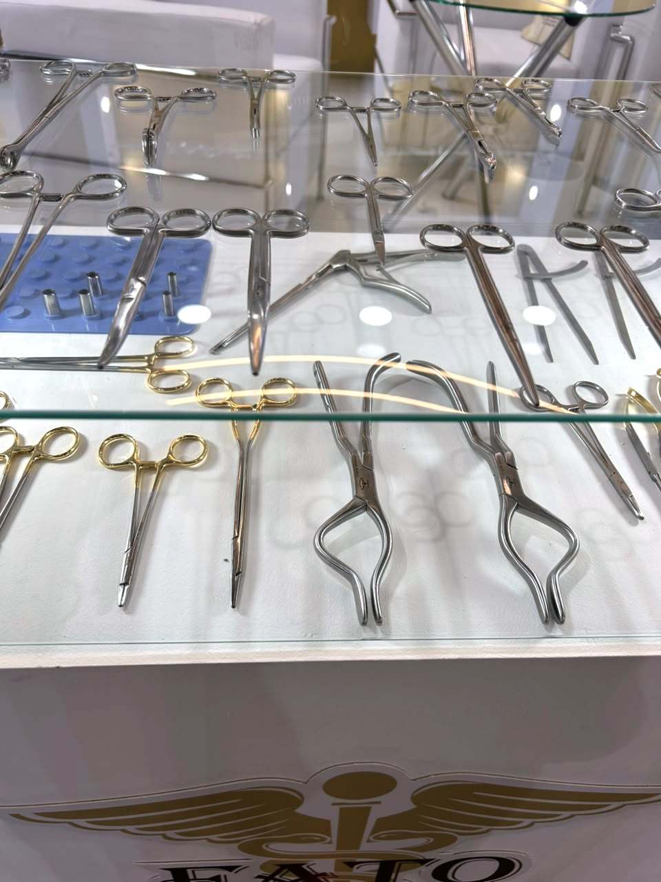 Vitrine com pinças, porta-agulhas e tesouras, várias com argolas douradas.
